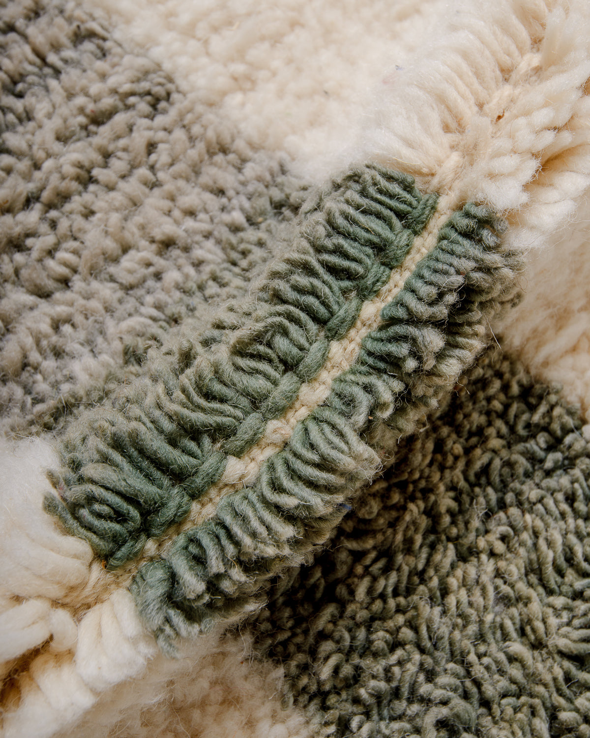Detail of cream and sage green plush wool rug showing the density of the knots.